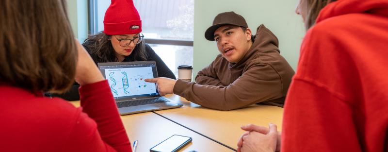 Students collaborating in a classroom while using a computer on the Aims Greeley campus