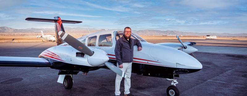 Aims aviation student in front of an airplane