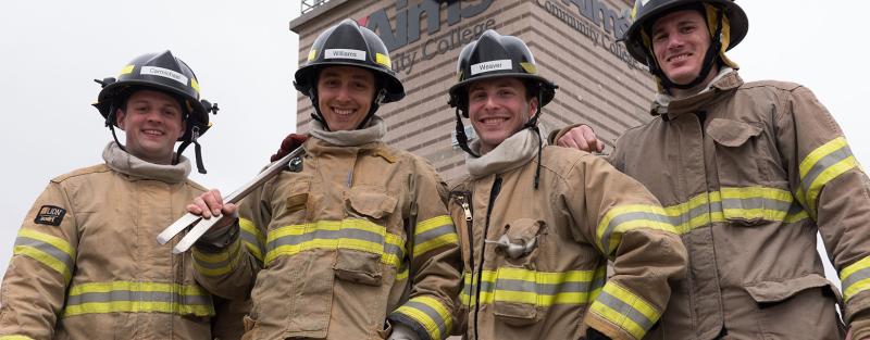 Aims fire academy students smiling and posing for a group photo wearing gear