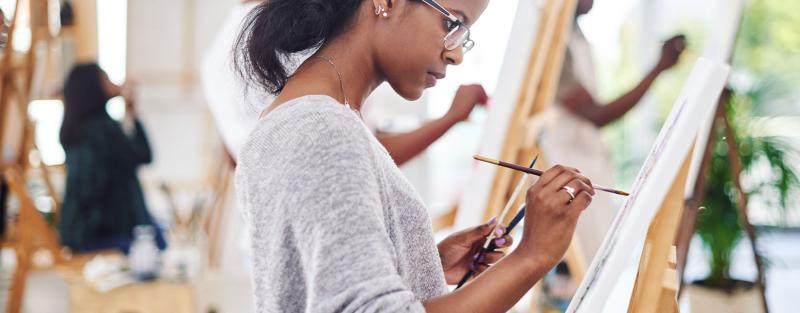 Liberal Arts student at Aims painting a canvas.