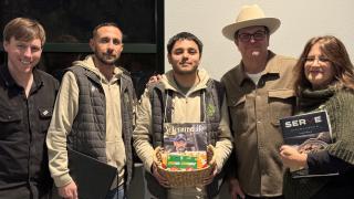 5 veterans standing side by side one in center holding a basket with books