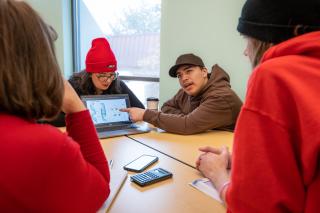 Students collaborating in a classroom while using a computer on the Aims Greeley campus
