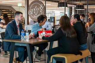Aims students and faculty sitting at a table in Arty's bistro drinking coffee and talking