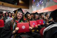 row of aims graduations holding their diplomas