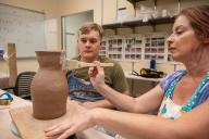 Woman painting pottery project with man watching