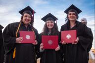 3 females in caps and gowns with diplomas