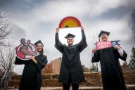 3 students in cap and gown with Aims signs