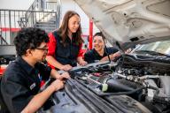Teacher and students looking at the engine of a truck.