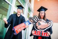 Aims students in cap and gown with All in and Aardvark Pride signs