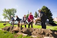 Five people digging dirt at groundbraking ceremony