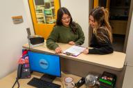 Two women looking at a clipboard on desk