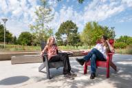 Two students sitting outside on the Aims Student Commons courtyard