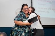 Two women hugging as one receives a certificate