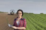 Woman in field holding laptop