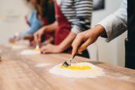 Closeup of hands mixing egg into flour with fork on wood counter