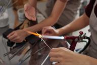 closeup of hands holding lit torch fusing glass