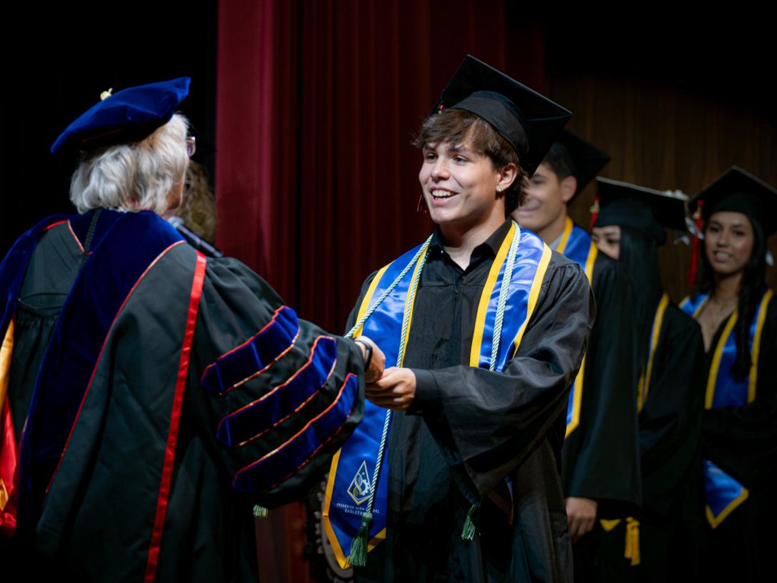 Student getting handed a diploma on stage
