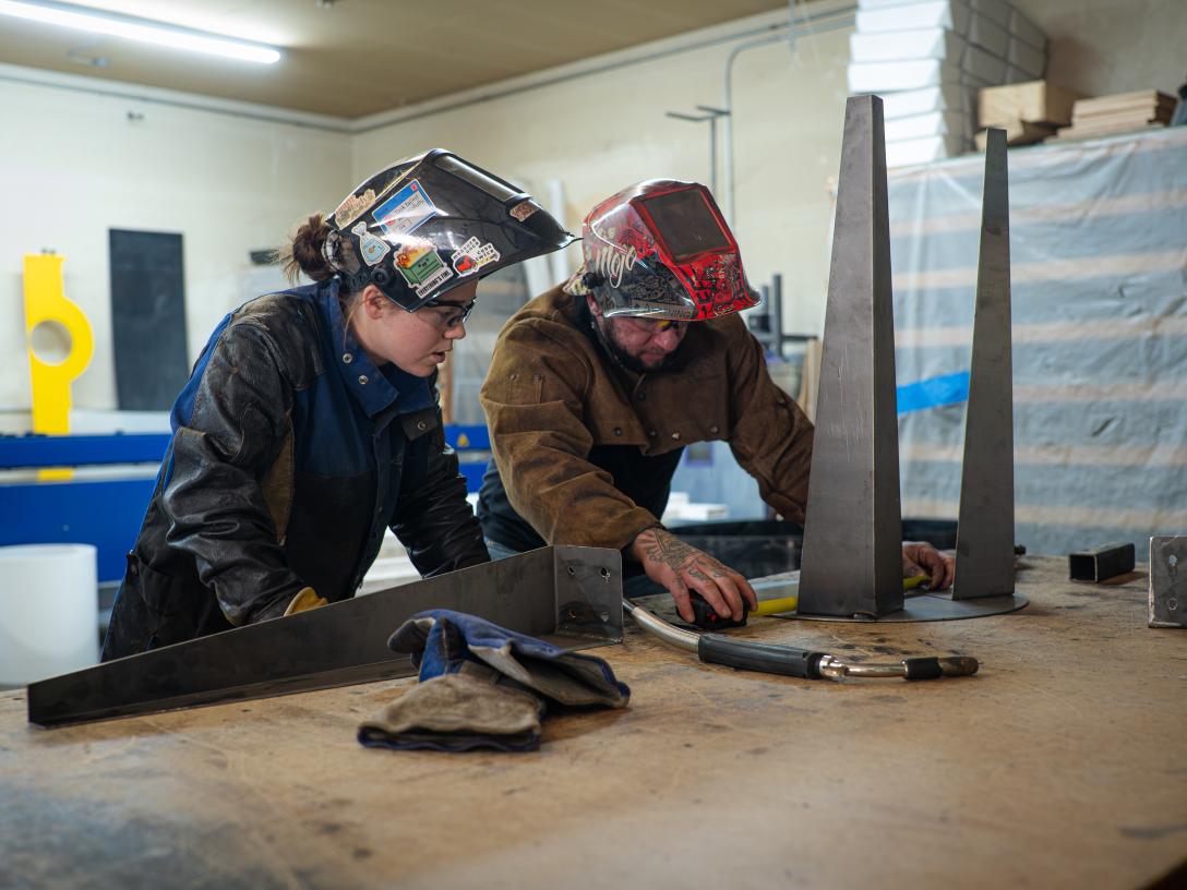 Man and woman inspecting welded metal