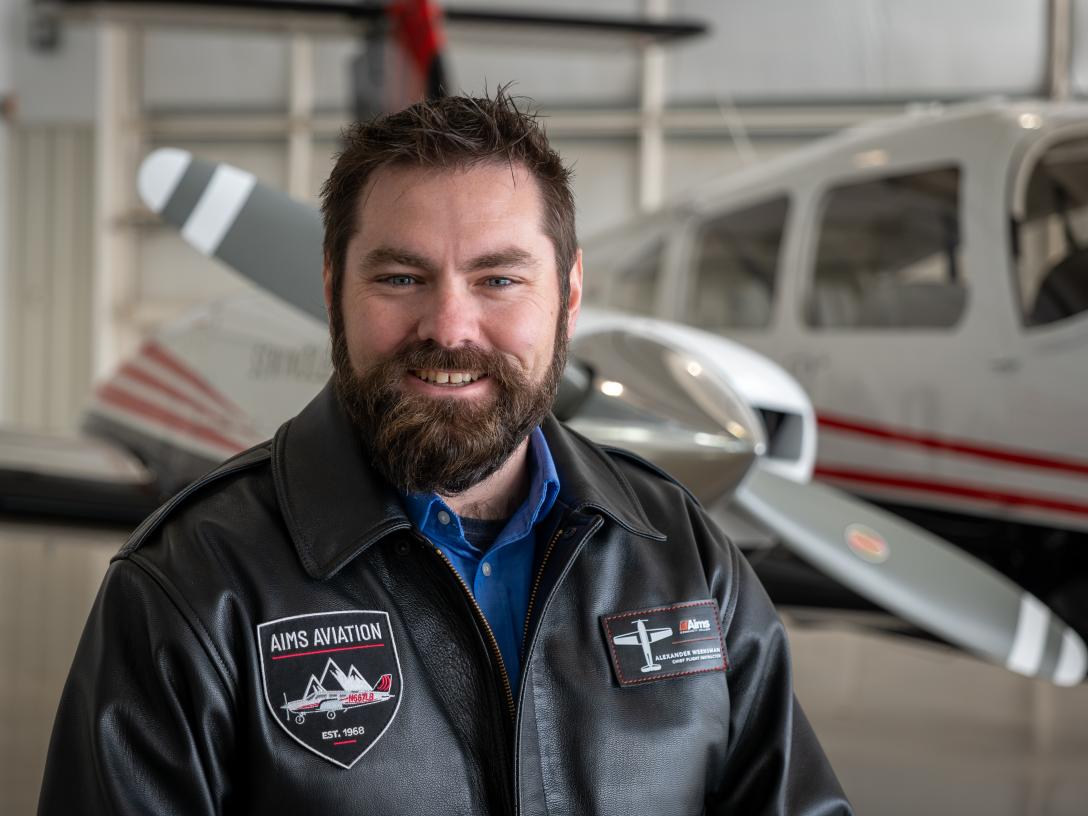Alex Wernsman, Chief Flight Instructor, Aims Community College aviation program standing in front of a plane