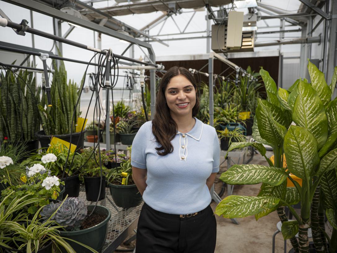 Felicia Gonzales-Soto portrait standing in greenhouse full of plants