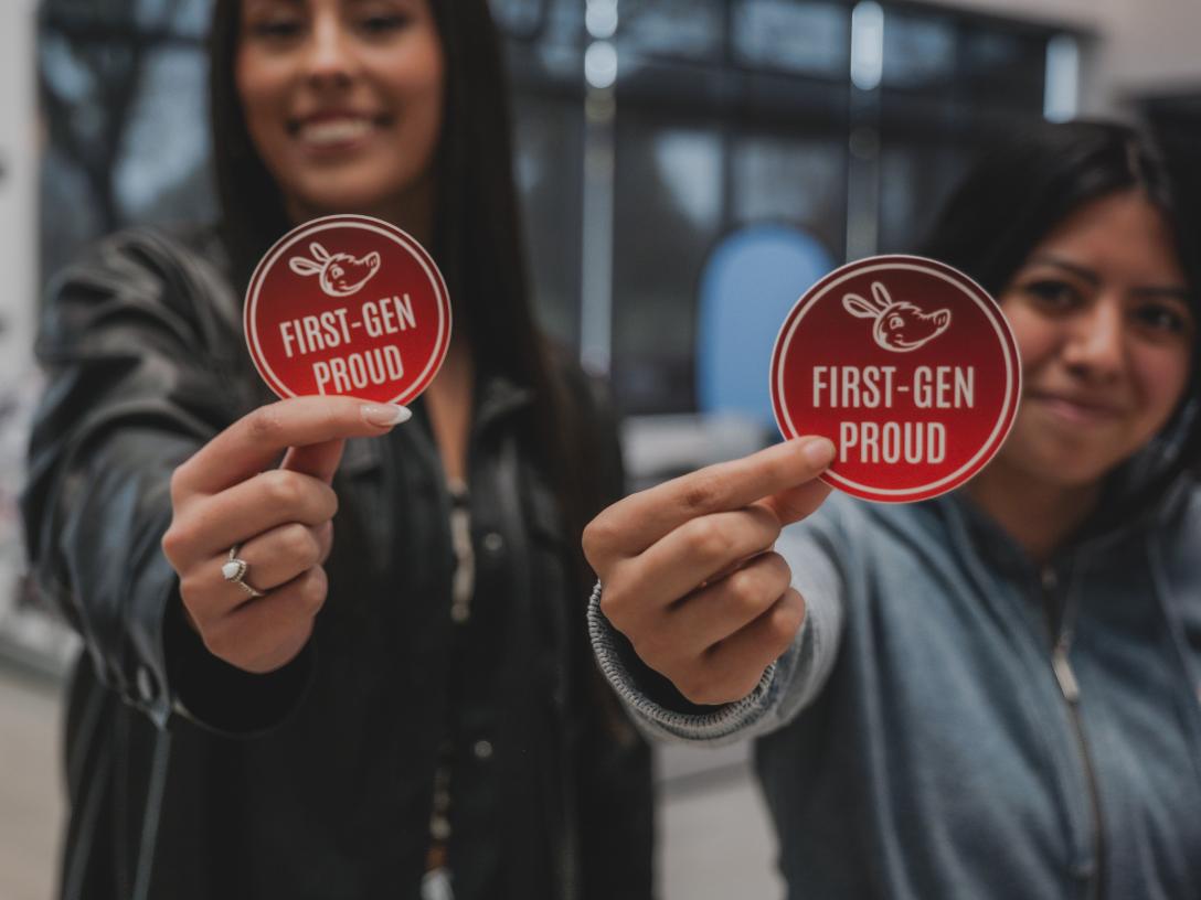 two females holding first gen proud sticker