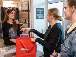 Two Students receiving items from Arty's Pantry staff