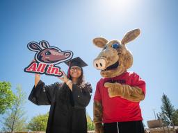 Arty and student in cap in gown with "All in" sign
