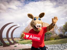 Arty the Aardvark Mascot at the Aims Greeley campus holding a sight that says I love Aims