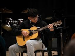 student playing an acoustic guitar
