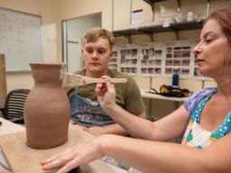 Woman painting pottery project with man watching