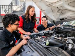 Teacher and students looking at the engine of a truck.