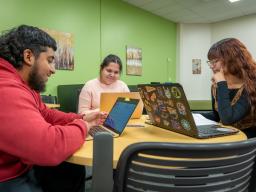 three students studying on laptops at a table