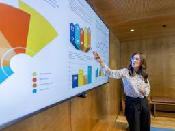 person pointing to graphs and data on a large screen