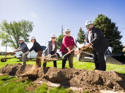 Five people digging dirt at groundbraking ceremony