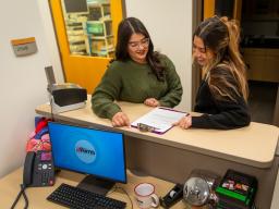 Two women looking at a clipboard on desk