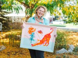Aims alumna Mel Calderon holding one of her paintings