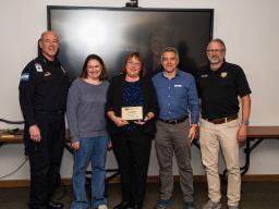 five people standing with award