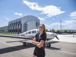 Samantha Walsh with plane and Aims Flight Training Center in the background