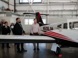Hickenlooper and Aims staff looks at airplane in hanger