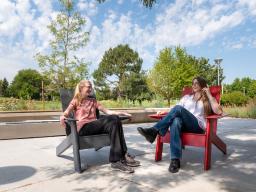 Two students sitting outside on the Aims Student Commons courtyard