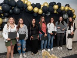 students standing with awards against balloon backdrop