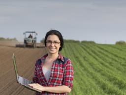 Woman in field holding laptop