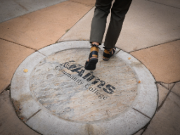 Person walking over Aims sidewalk logo
