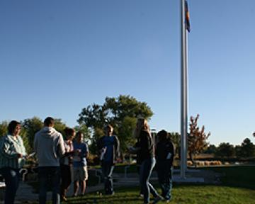 Aims Ambassadors for Christ student club members in a prayer circle at a flagpole.
