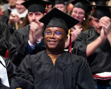 Student smiling in cap and gown during commencement ceremony