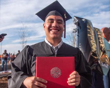 Aims Graduate in cap and gown smiling with diploma