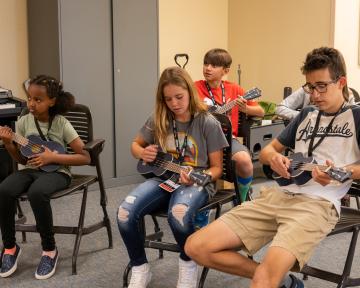 Students learning how to play the ukulele at College for Kids