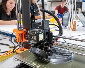 machine working in community lab, students in the background