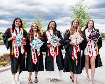 females in with decorated graduation caps outside of the Welcome Center
