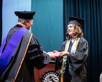graduate getting presented a diploma on stage at commencement